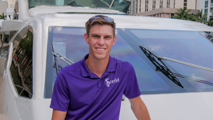 Eric Ellson​ in a purple shirt standing in front of a white car