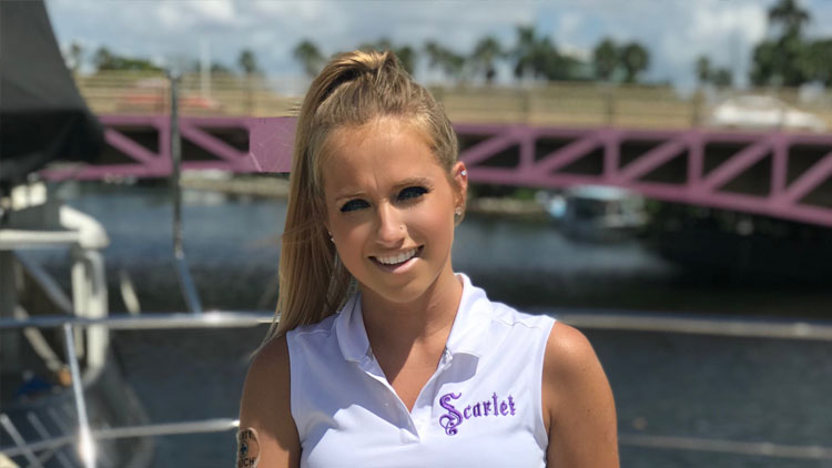 Katie Glasser​ standing on a boat in front of a bridge